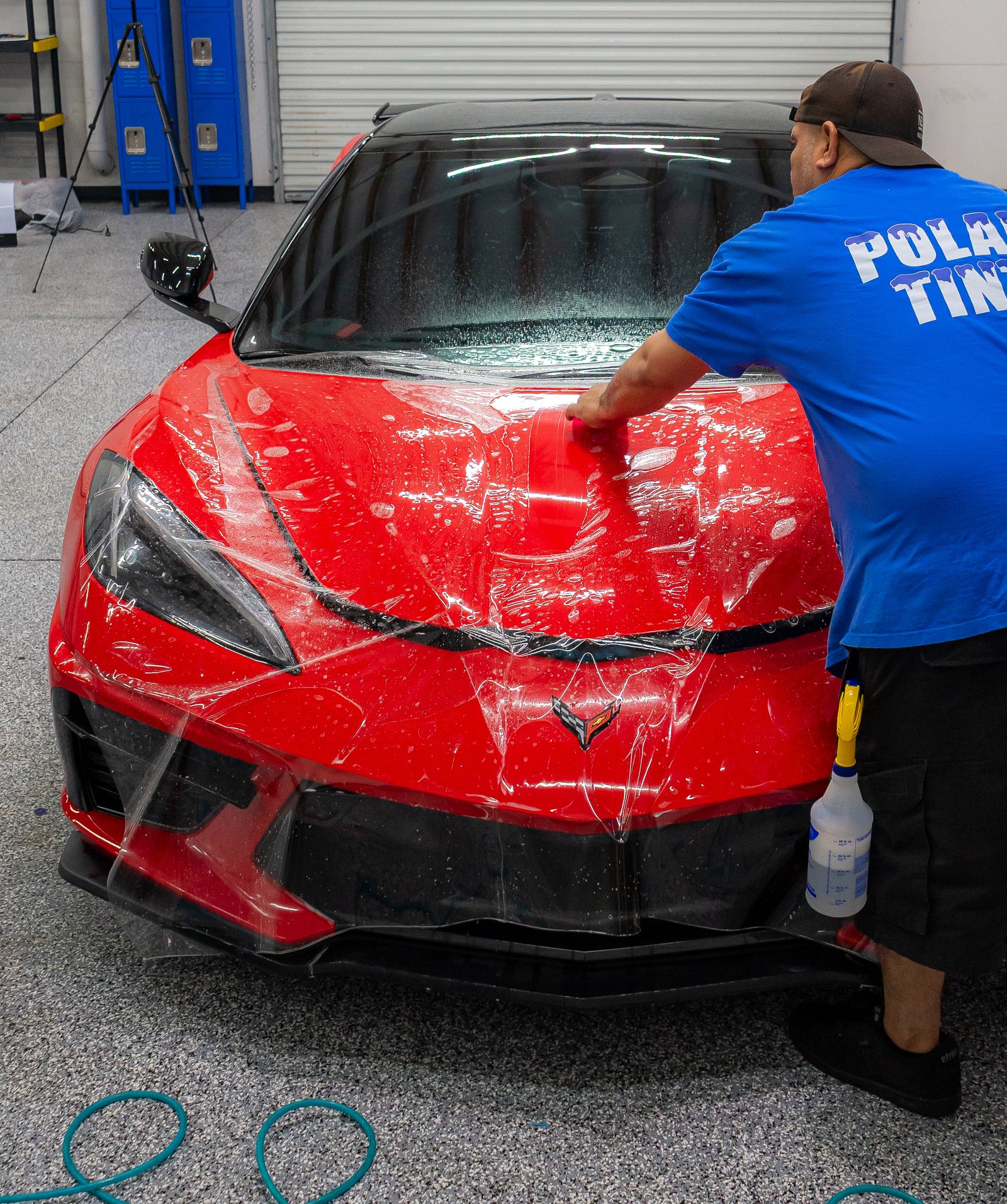 Polar Tint technician applying paint protection film to a red Corvette