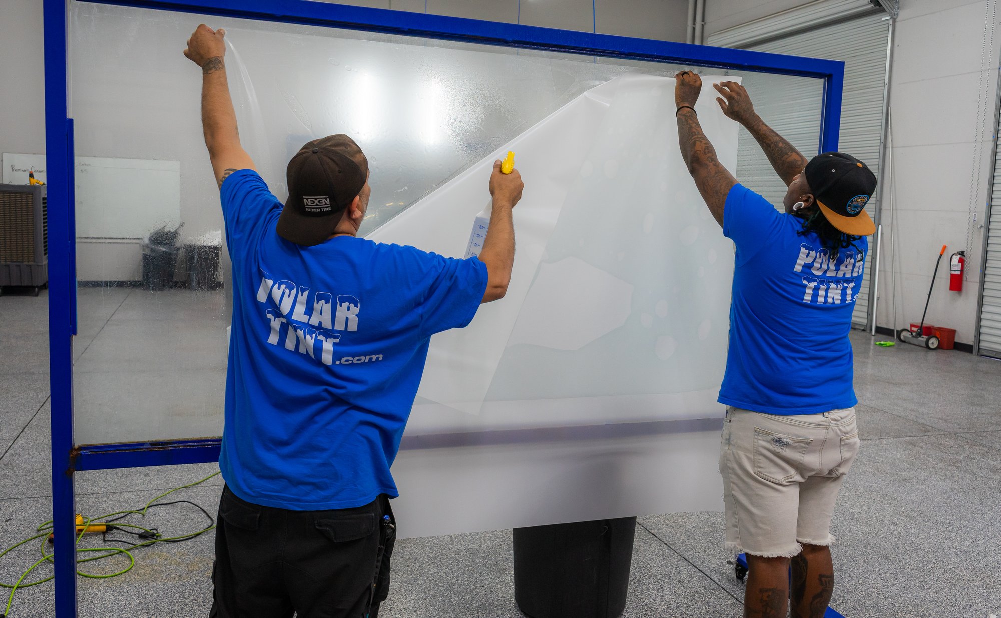 Two Polar Tint technicians training on a large commercial glass install